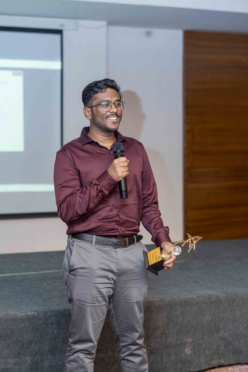 Yegappan Sekar giving a speech at the Web Wizard Award ceremony, holding a mic and trophy
